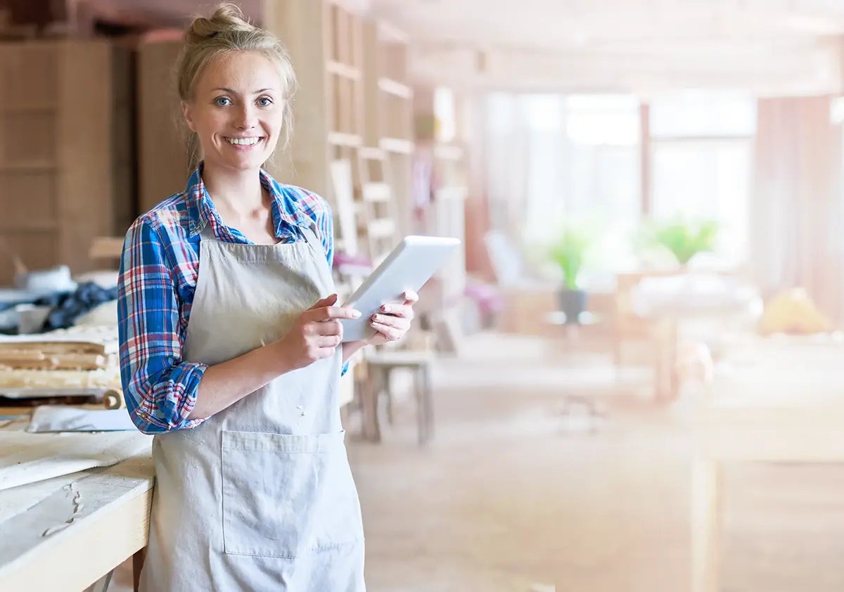 Handmade business owner holding craft product and looking at laptop